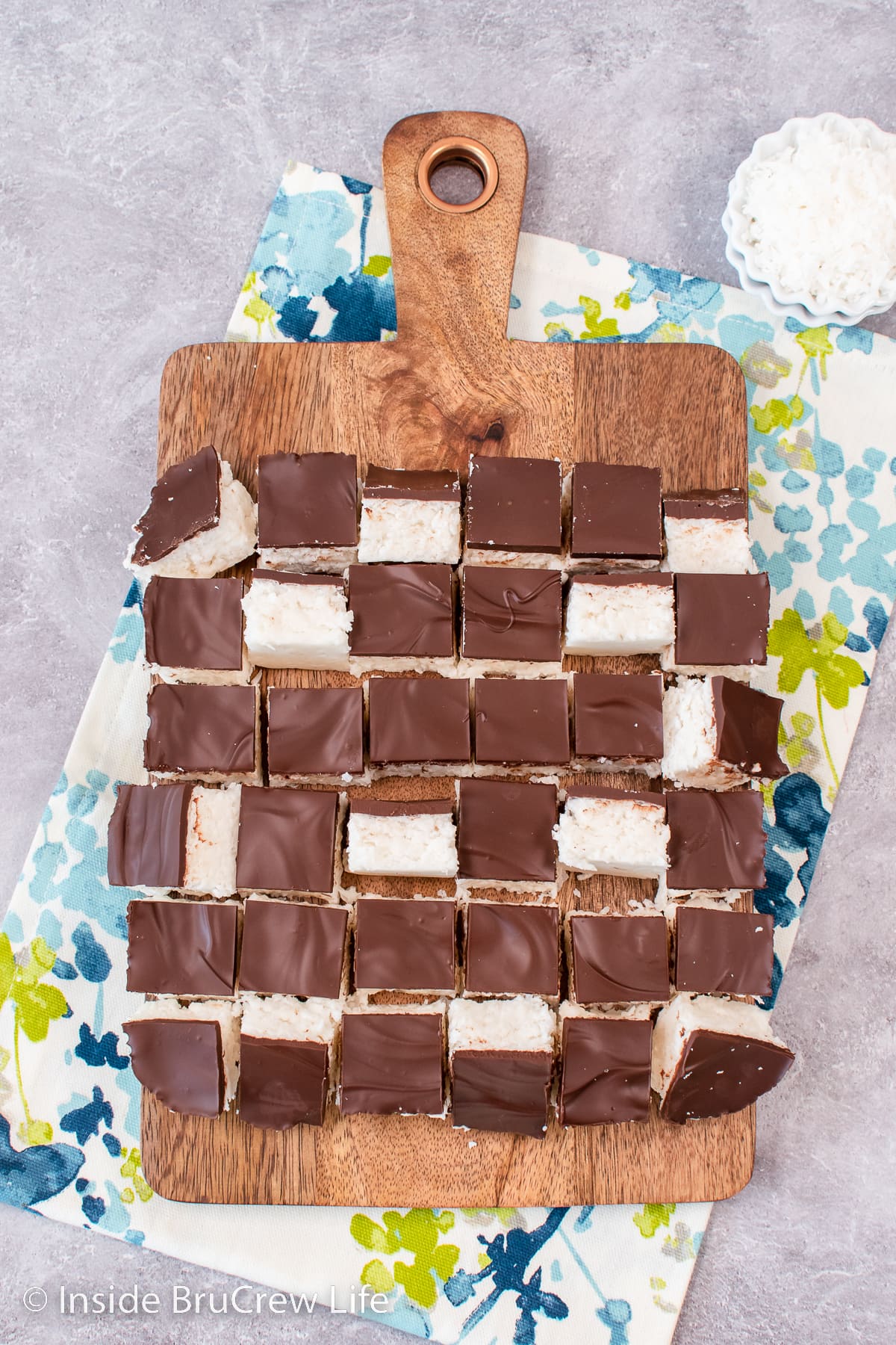 A brown tray with chocolate topped coconut potato fudge on it.