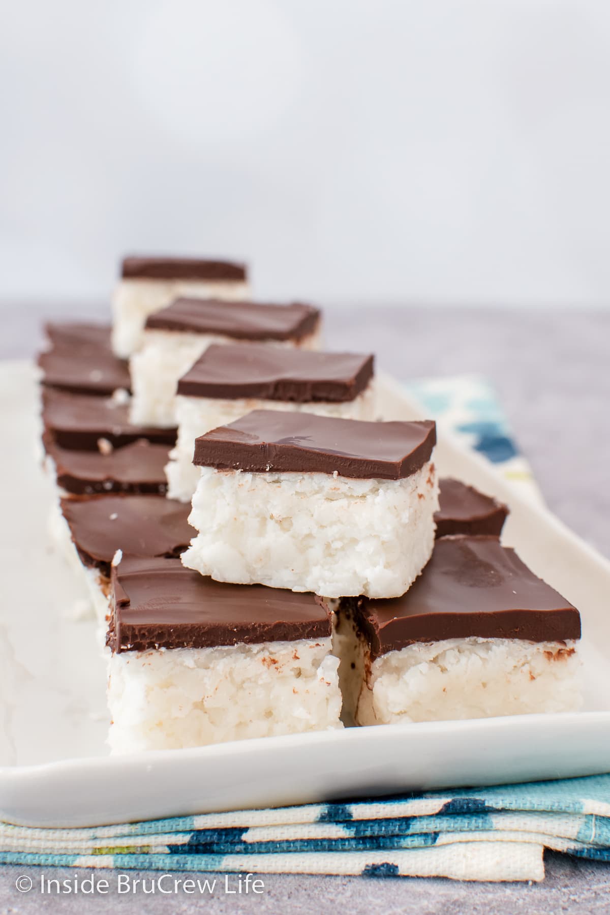 A white tray with chocolate topped potato fudge stacked on it.