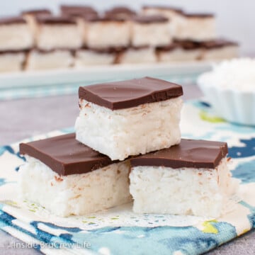 Three coconut fudge squares stacked on a blue towel.