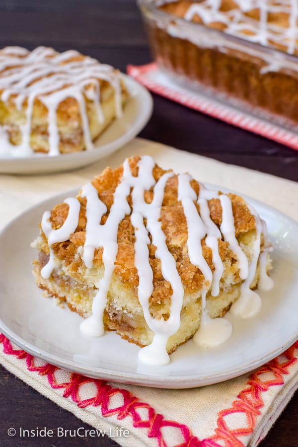 Two plates with sour cream coffee cake squares with a drizzle of glaze on top.