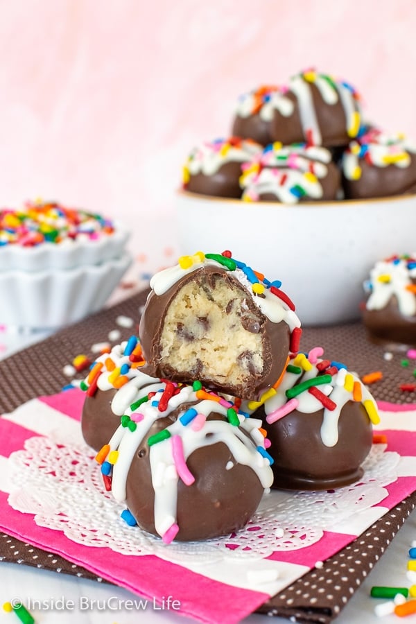 Cookie Dough Truffles dipped in chocolate and decorated with white chocolate and sprinkles on a white and pink napkin