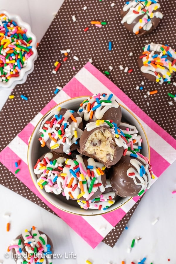 An overhead picture of a bowl filled with decorated chocolate chip cookie dough truffles.