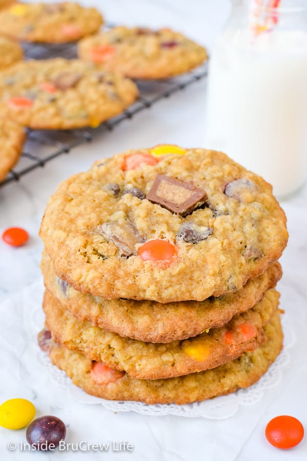 A stack of four peanut butter oatmeal banana cookies with a glass of milk behind it