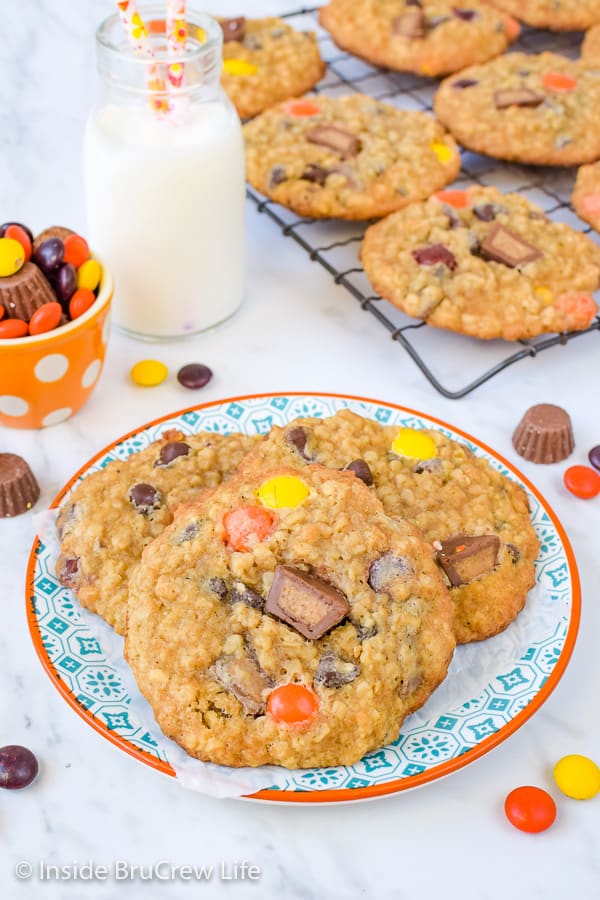 Three cookies piled on a plate with a wire rack with more cookies behind it