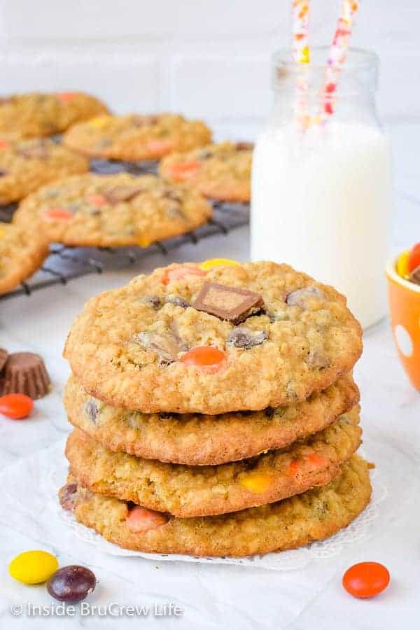 Four peanut butter banana cookies stacked on a white doily with a tray of cookies behind it