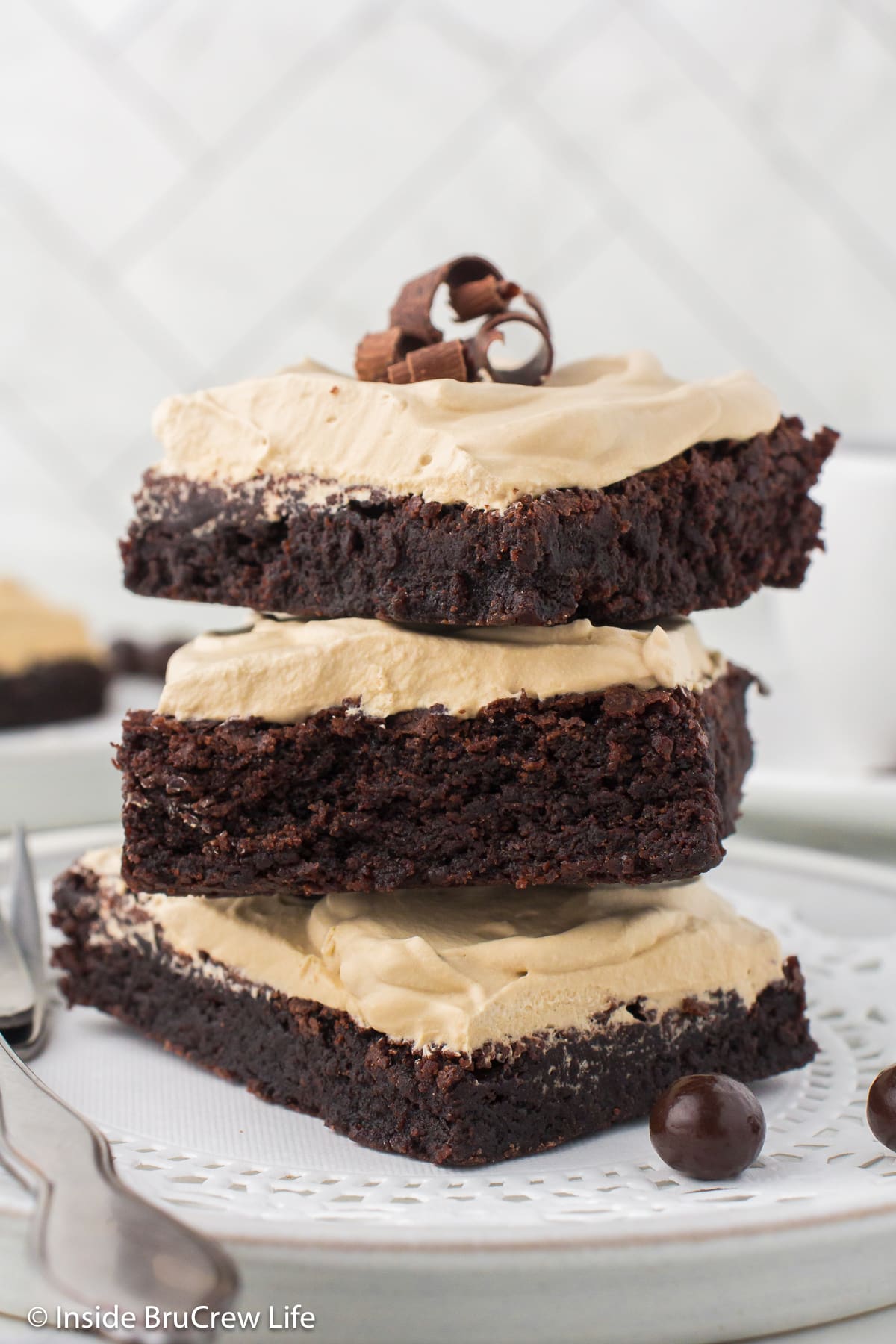 A stack of three frosted chocolate bars on a plate.