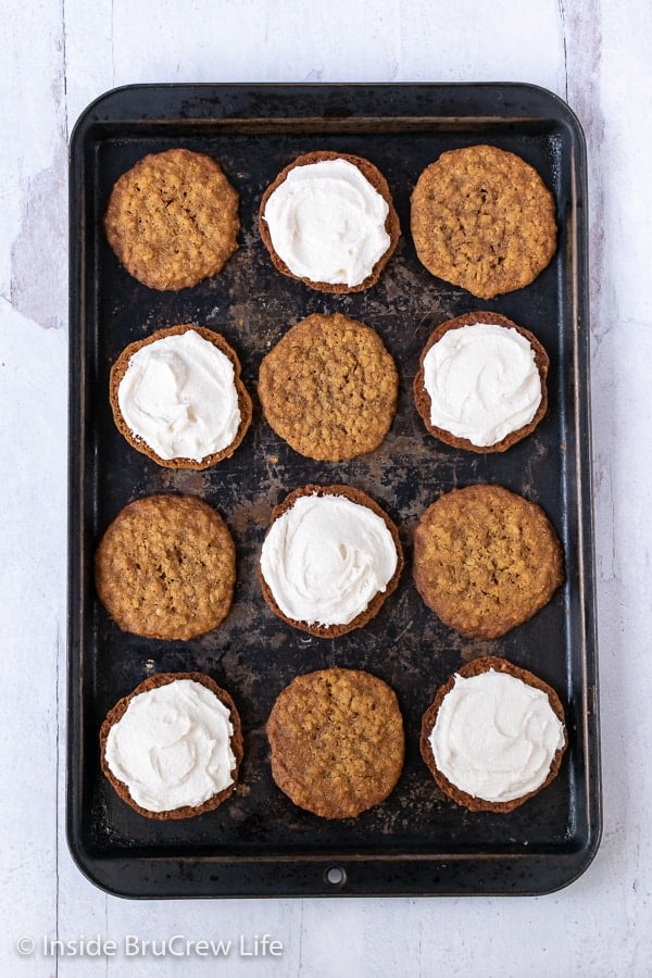 Overhead picture of a metal baking sheet with oatmeal cookies with filling on it