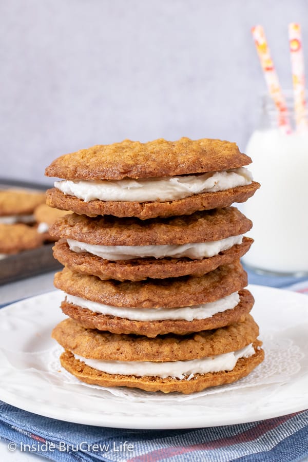 Four oatmeal creme pie cookies stacked on top of each other on a white plate.