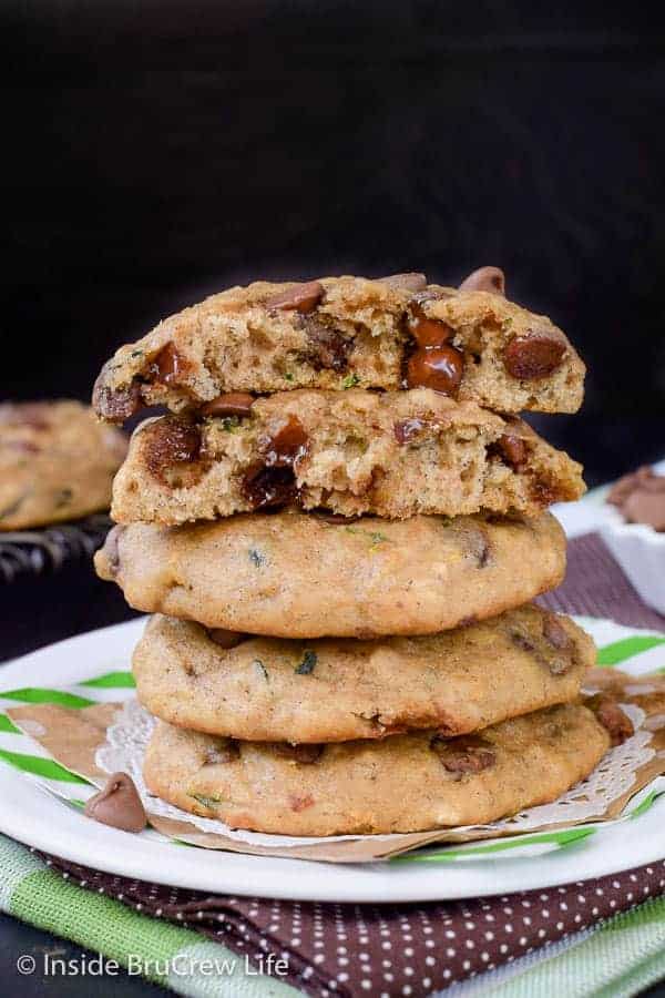 A stack of banana chocolate chip zucchini cookies on a white plate with the top cookie broken in half.