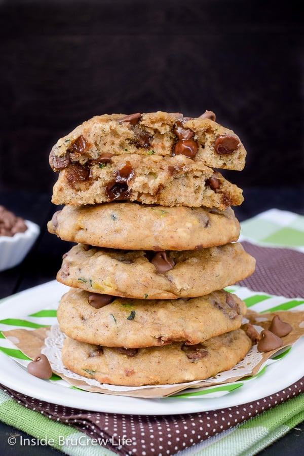 A stack of banana zucchini cookies on a white plate with the top cookie broken in half.