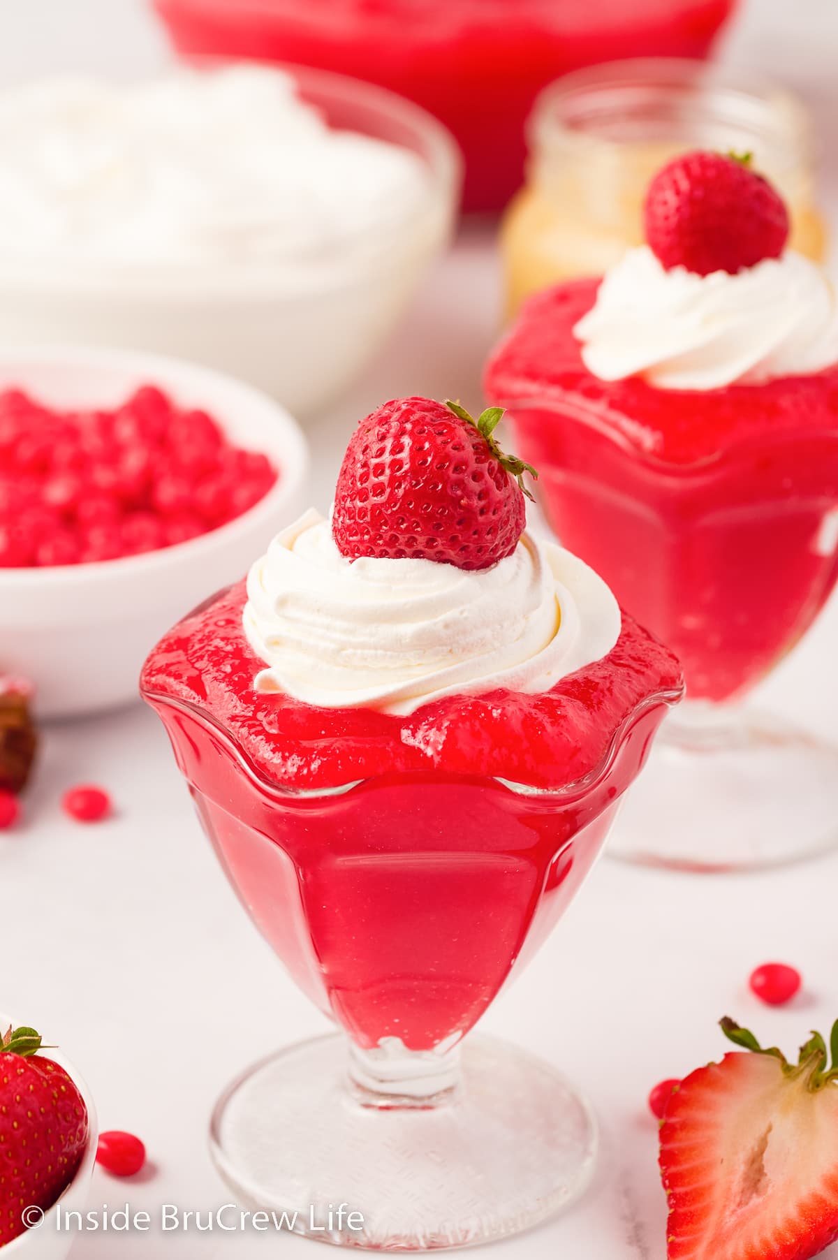 Two clear glass dishes with cinnamon Jello topped with whipped cream.