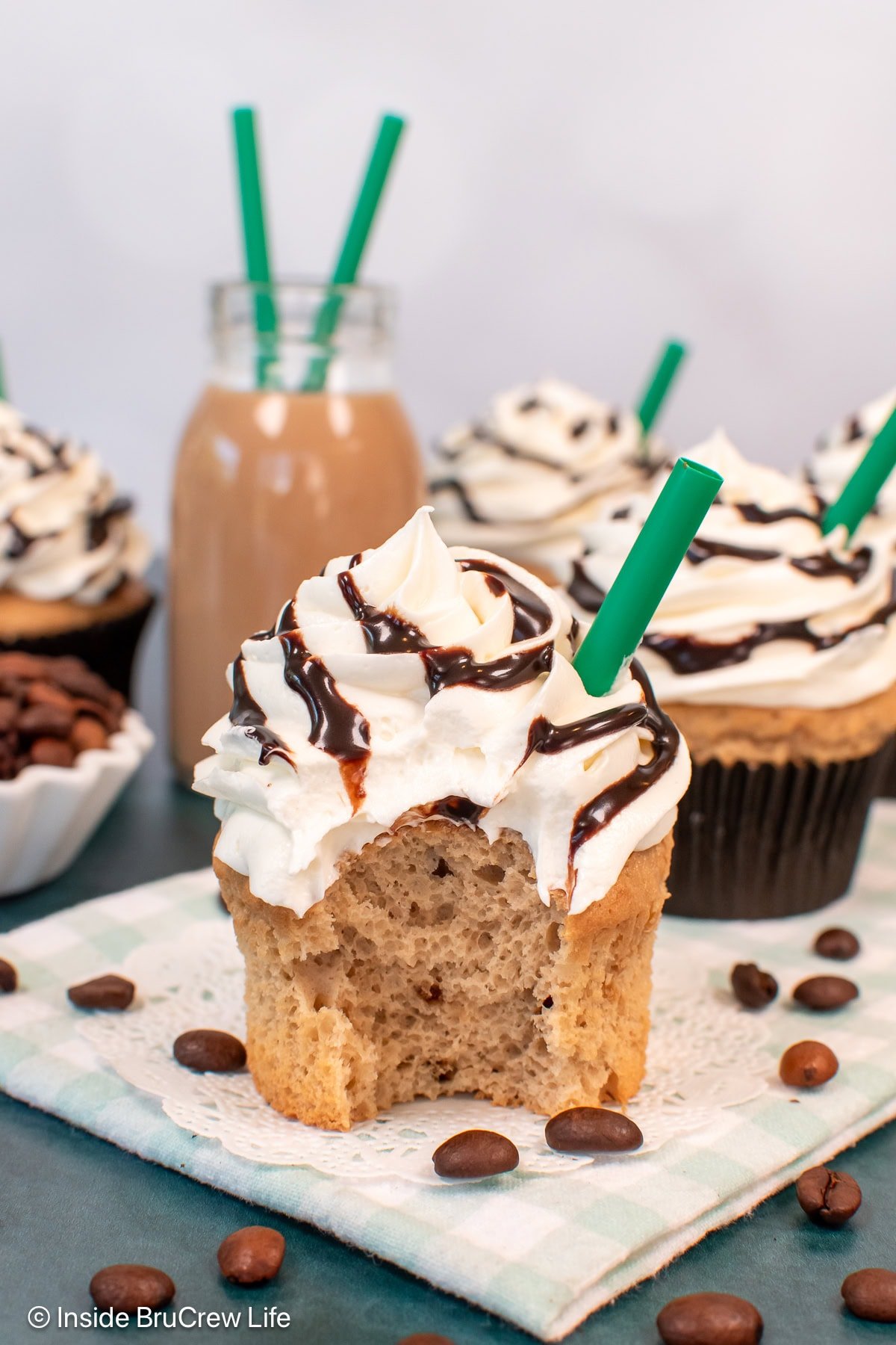 A frosted coffee cupcake with a bite taken out of it.