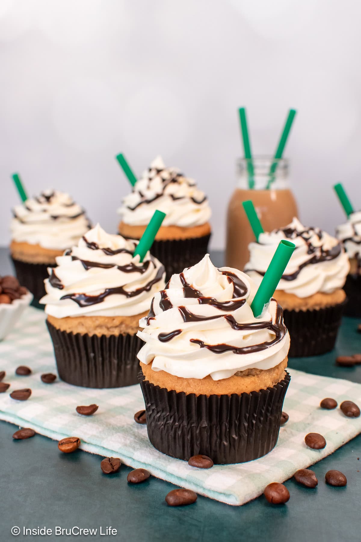 Frosted white chocolate mocha cupcakes on a green board.