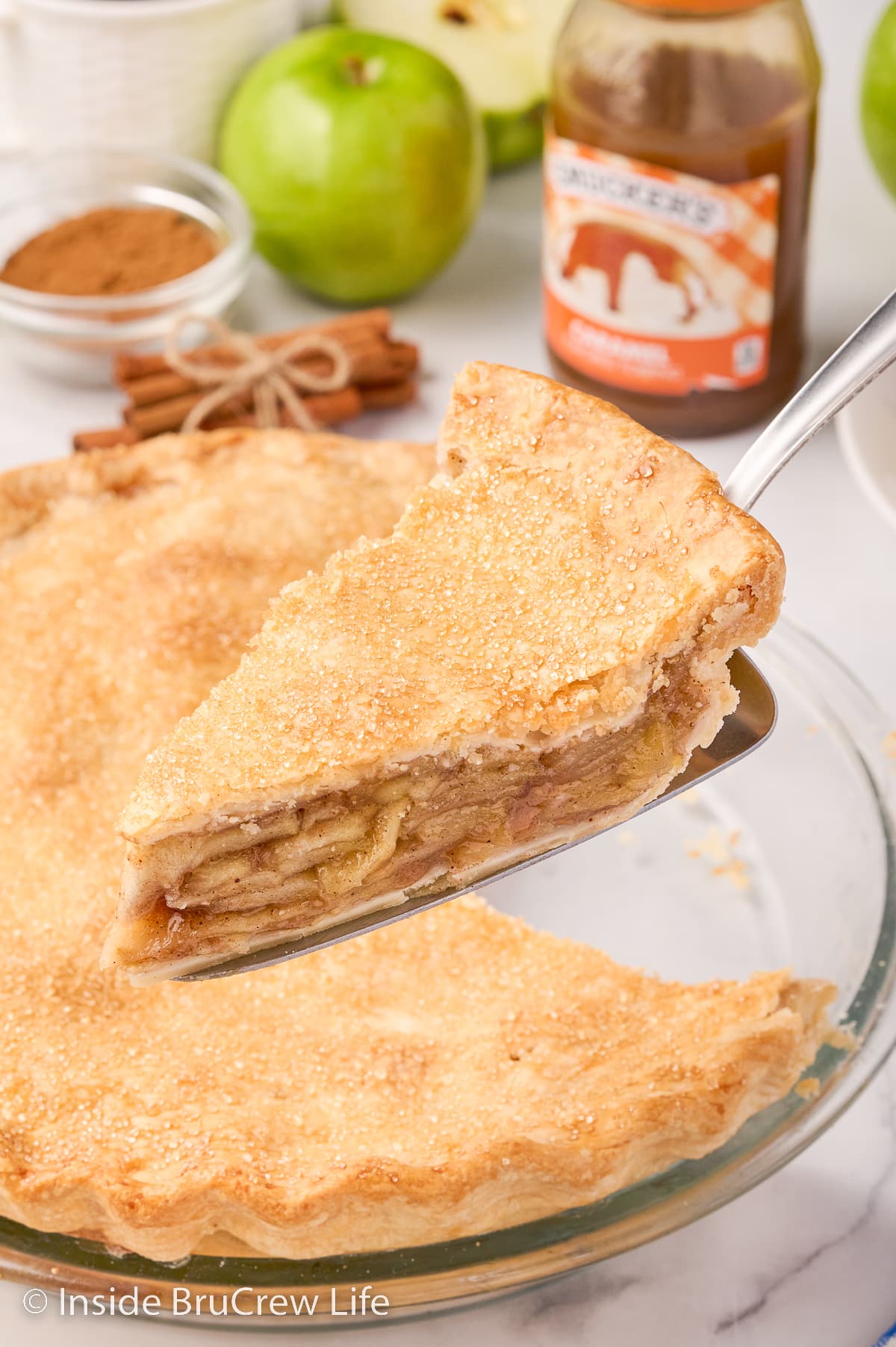 A slice of apple pie being lifted out of the pan with a spatula.