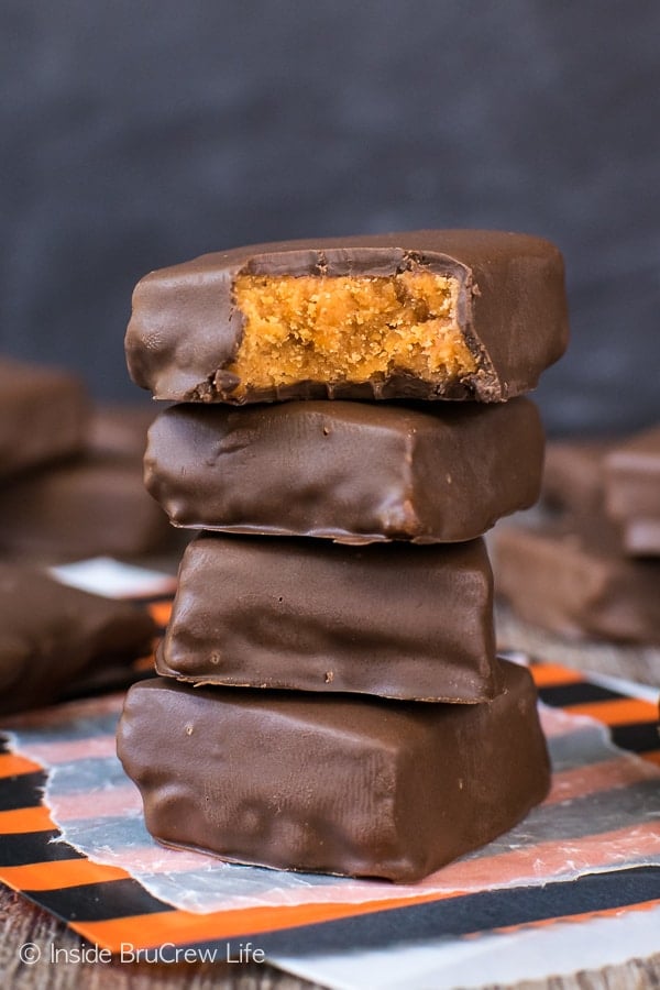 A stack of chocolate covered Butterfinger bars stacked on top of each other. The top one has a bite out of it showing the filling inside.
