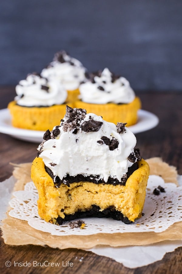 A white doily with a pumpkin Oreo cheesecake topped with Cool Whip and missing a bite on it