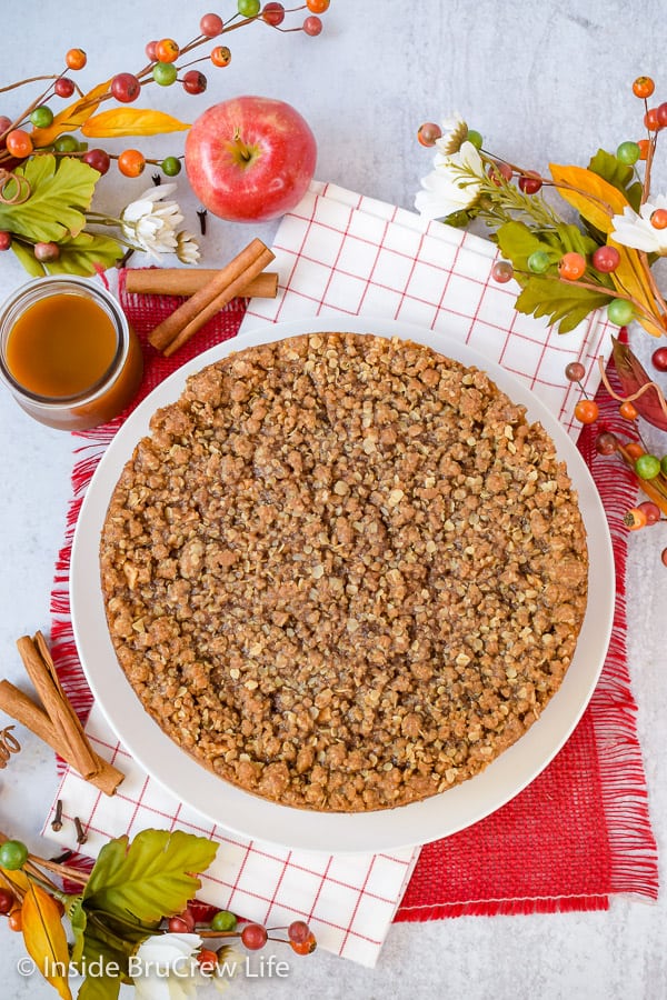 Overhead picture of a full apple crisp cheesecake on a white plate.