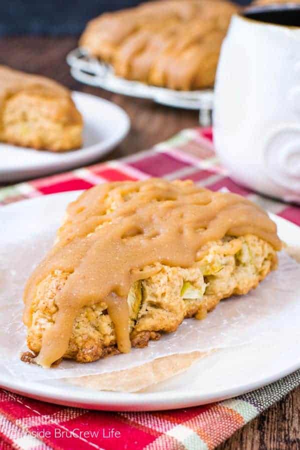 A white plate with a caramel apple scone on it and more scones behind it