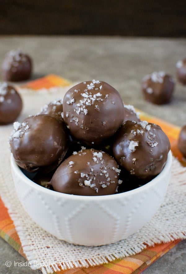 A white bowl filled with salted caramel brownie bites with sea salt on top of each one