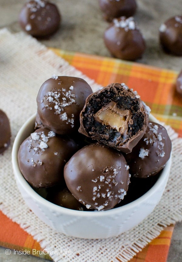 An overhead picture of a white bowl filled with salted caramel brownie bites with a bite out of the very top one