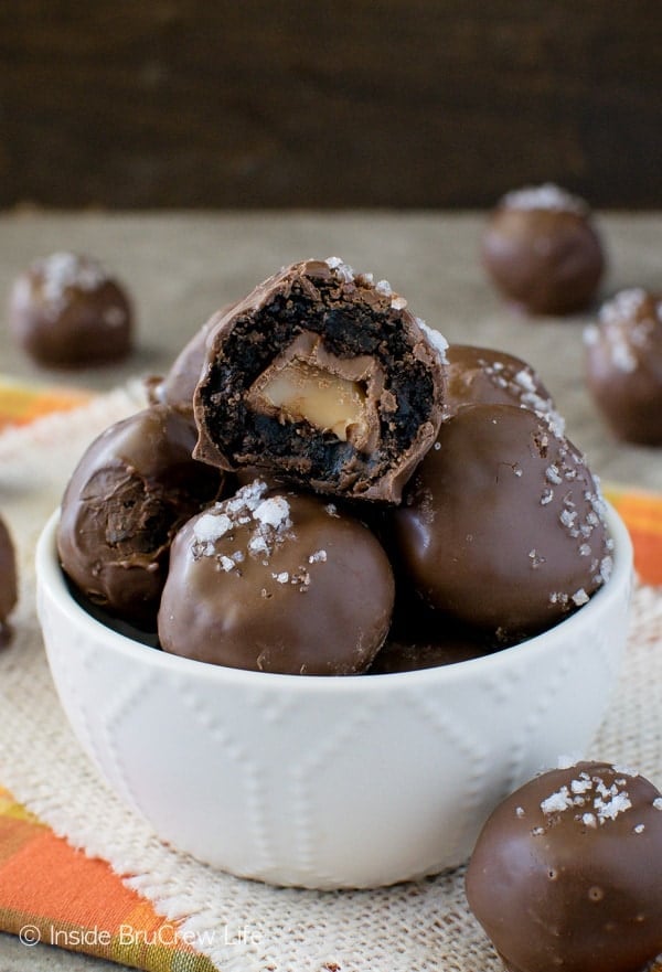 A white bowl filled with salted caramel brownie bites with one on top with a bite out it