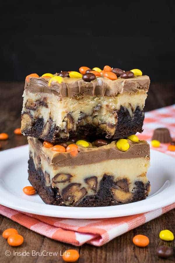 Two cheesecake brownie squares stacked on a white plate.