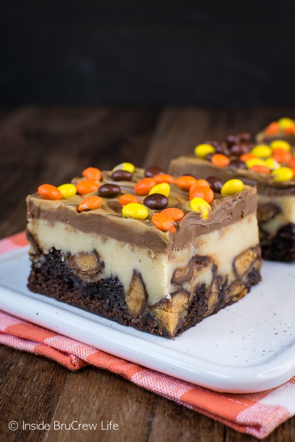 A white plate with squares of peanut butter cheesecake brownies on it.