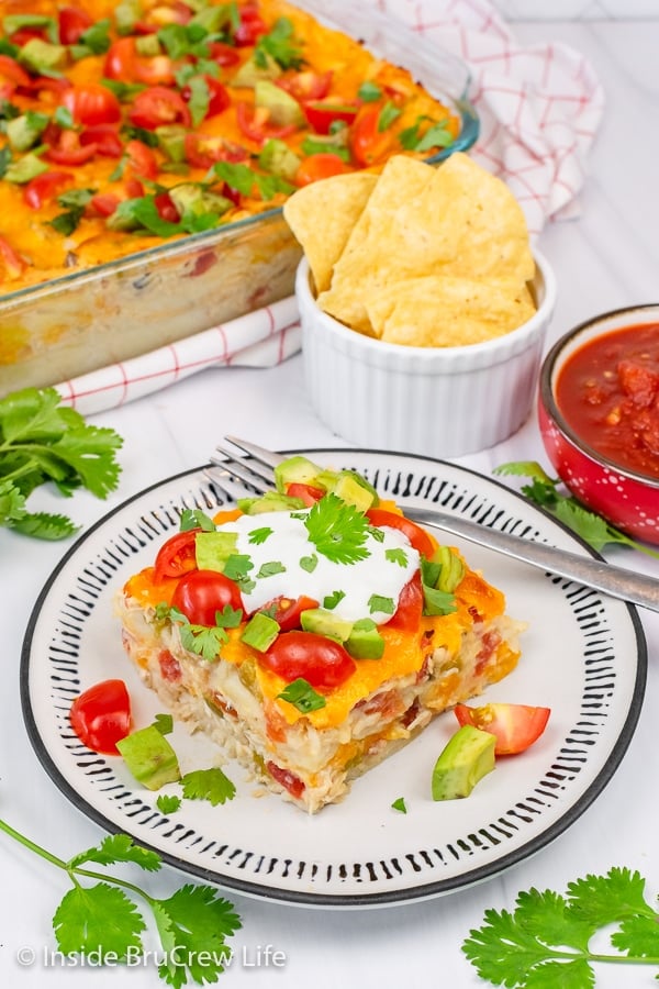 A white plate with chicken ole casserole topped with a layer of melted cheese and toppings.
