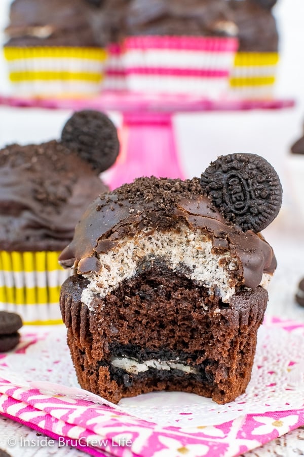 A close up of a chocolate cupcake with an Oreo on the bottom and Oreo buttercream plus chocolate frosting on top with a bite out of the cupcake