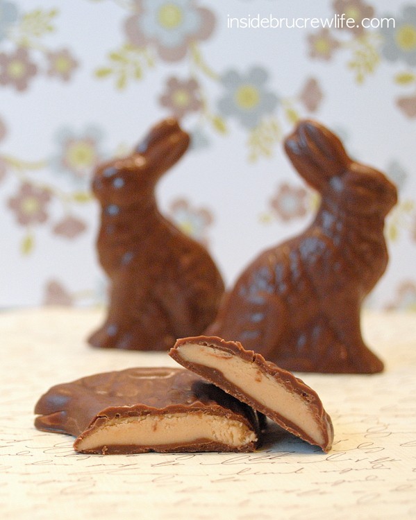 2 chocolate Easter bunnies in the background with one laying down cut open to reveal the peanut butter center.