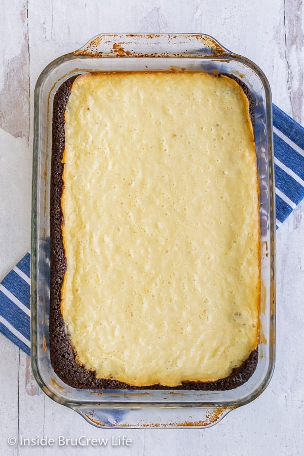 Overhead picture of a pan of coconut cream cheesecake brownies on a white background