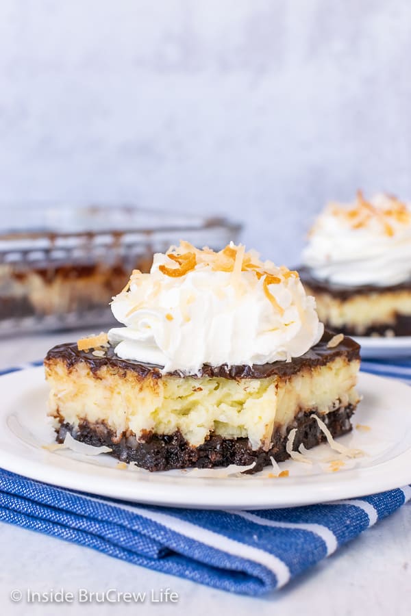 A piece of Coconut Cream Cheesecake Brownies on a white plate with a bite taken out of the front