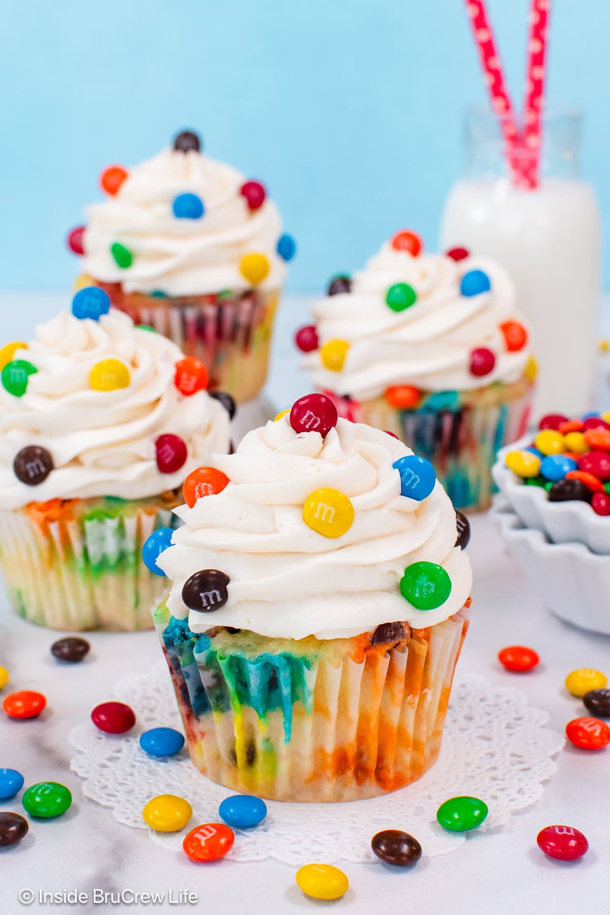 Four vanilla cupcakes with M&M candies.