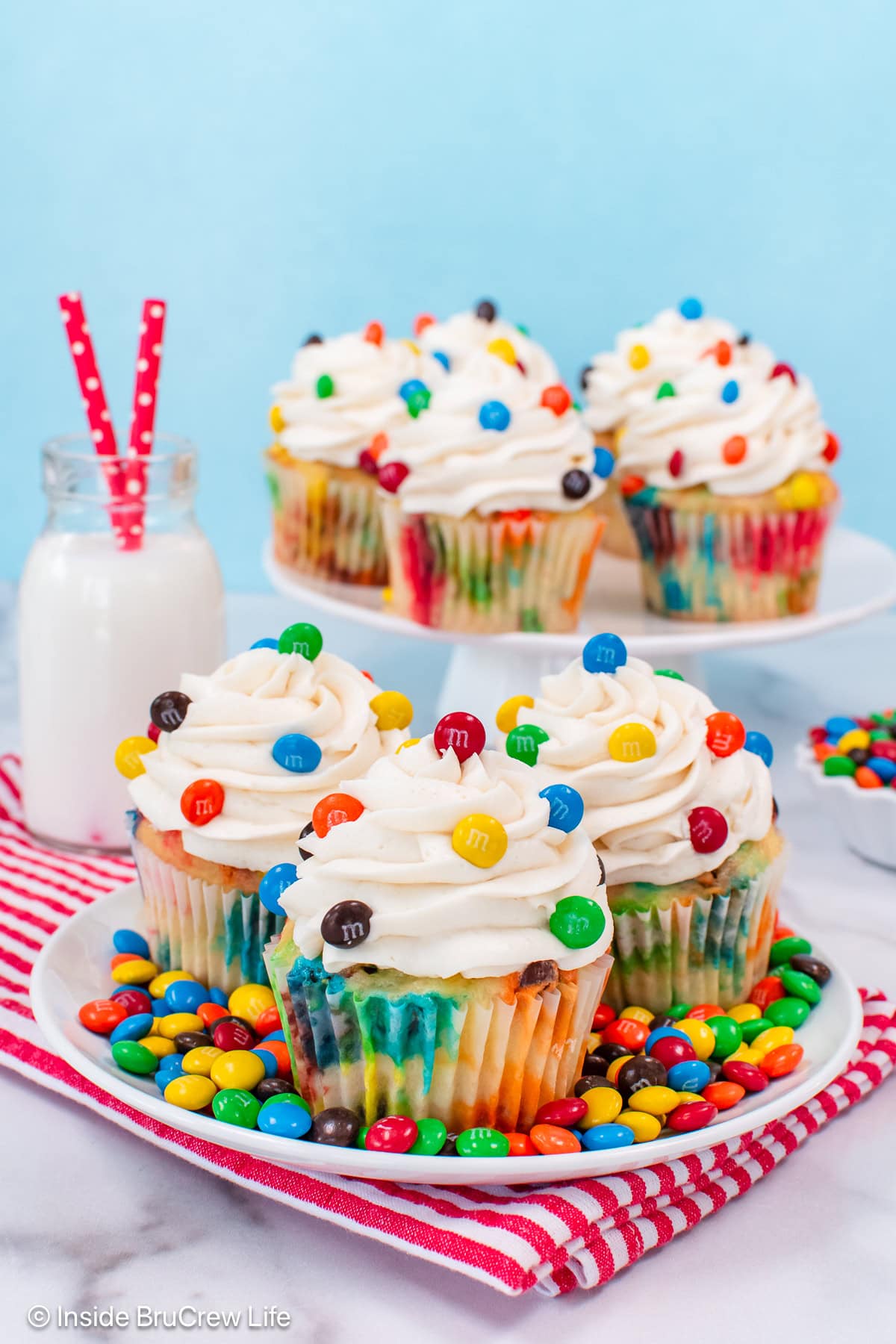M&M cupcakes on a plate with candies around them.