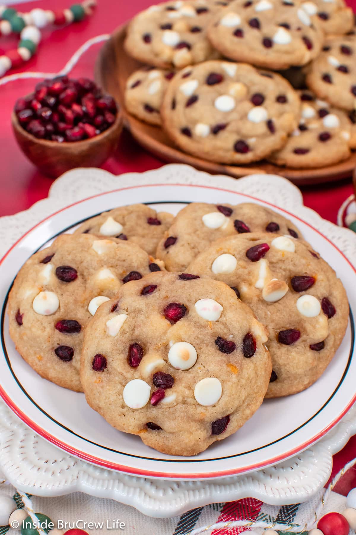 A white plate with white chocolate chip cookies on it.
