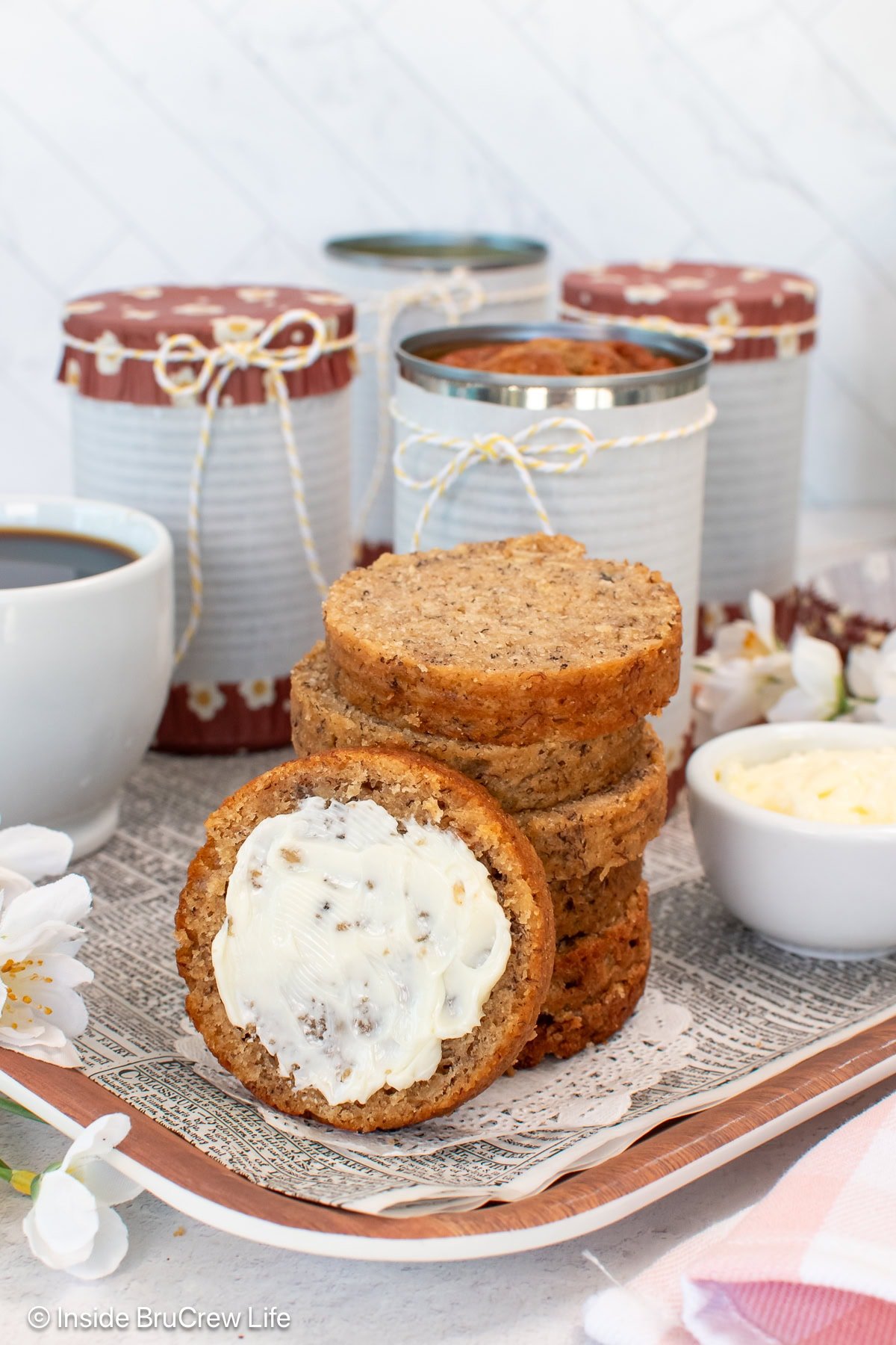 Slices of can banana bread stacked on top of each other with a buttered slice beside it.