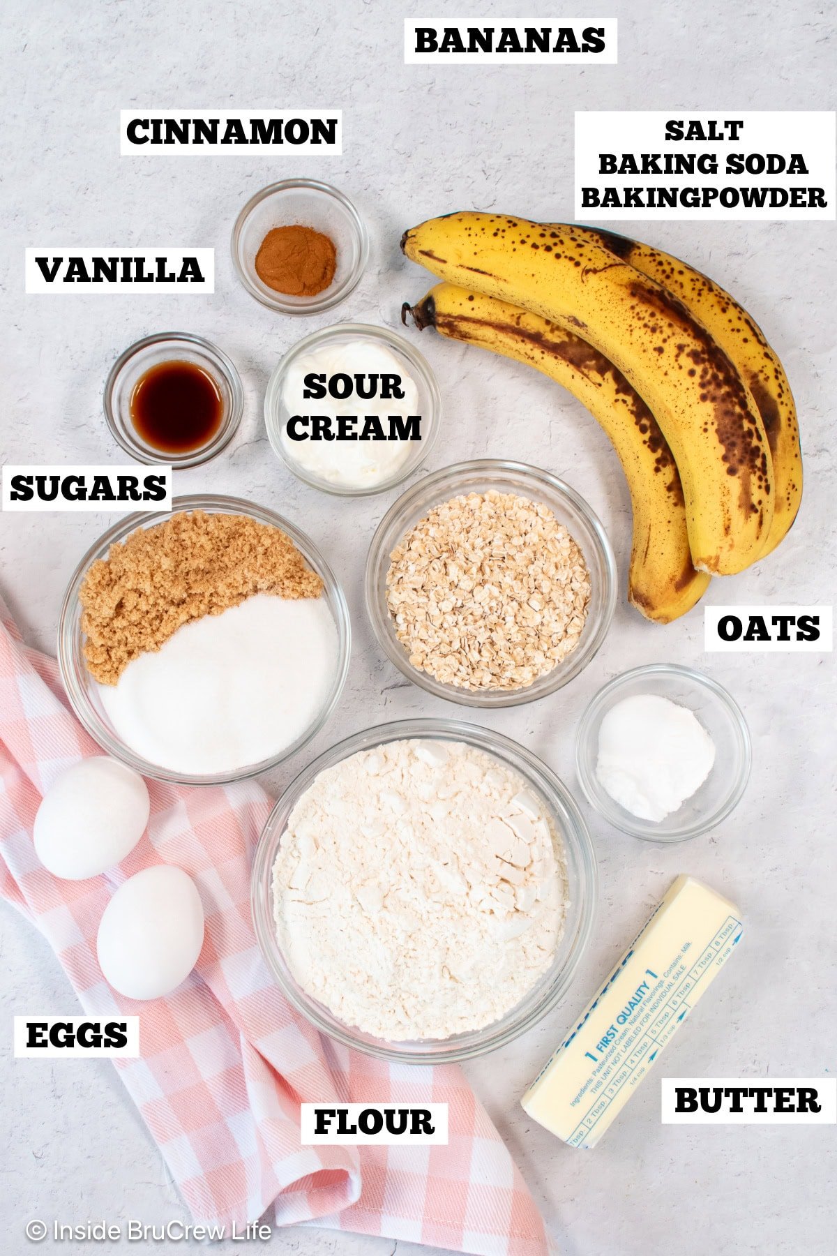 A white board with bowls of ingredients needed to make banana bread.