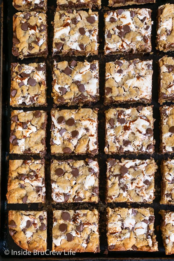 An overhead picture of lots of squares of Peanut Butter S'mores Blondies on a dark sheet pan