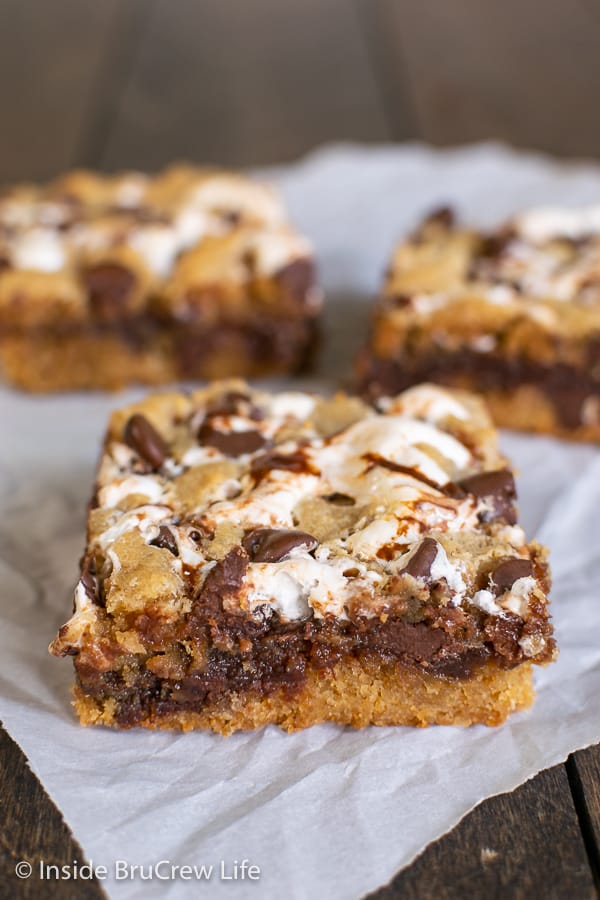 Close up picture of a Peanut Butter S'mores Blondie on a piece of parchment with two other blondies behind it