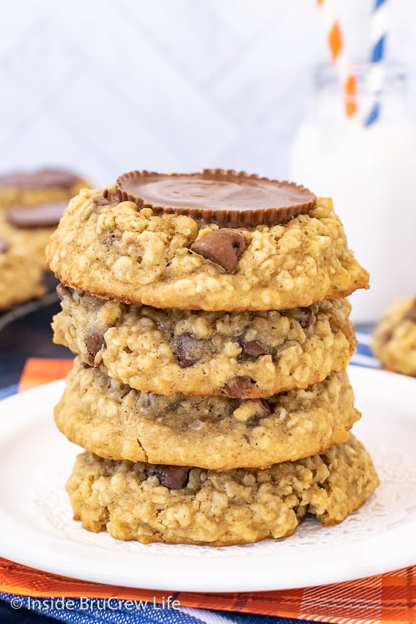 A white plate with a stack of four oatmeal banana cookies topped with peanut butter cups on it