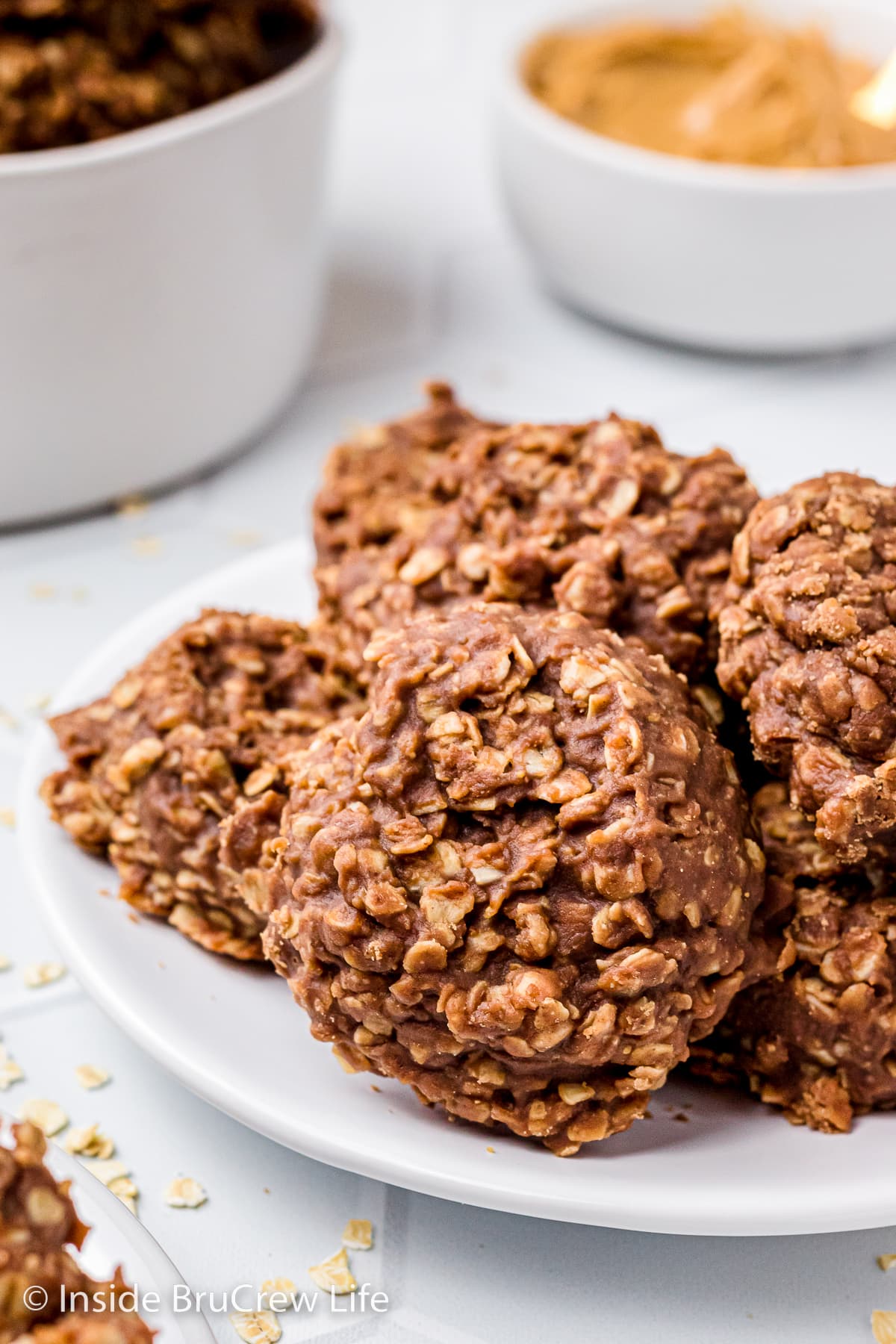 A white plate with a stack of chocolate oatmeal drop cookies on it.