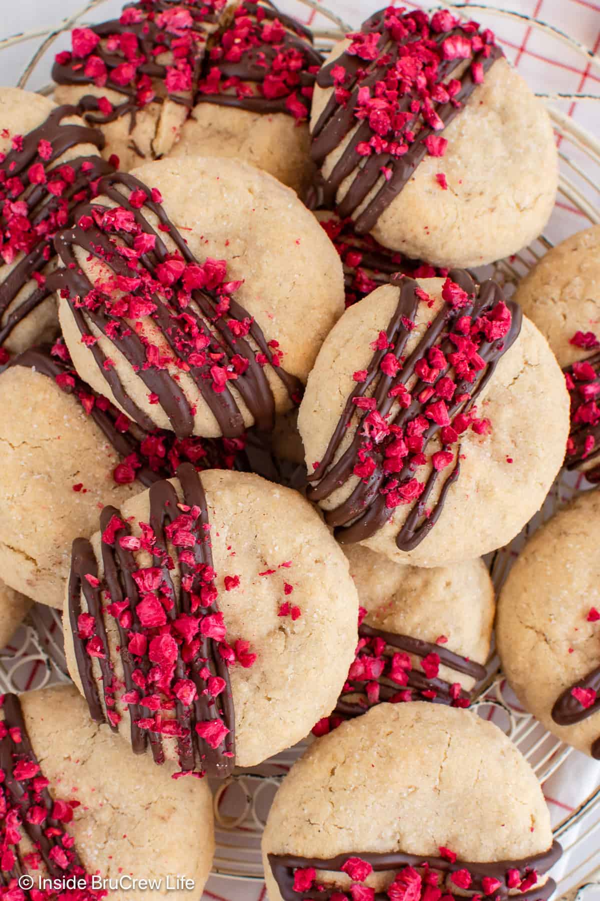 A tray of raspberry cookies with chocolate drizzles and freeze dried raspberry pieces.