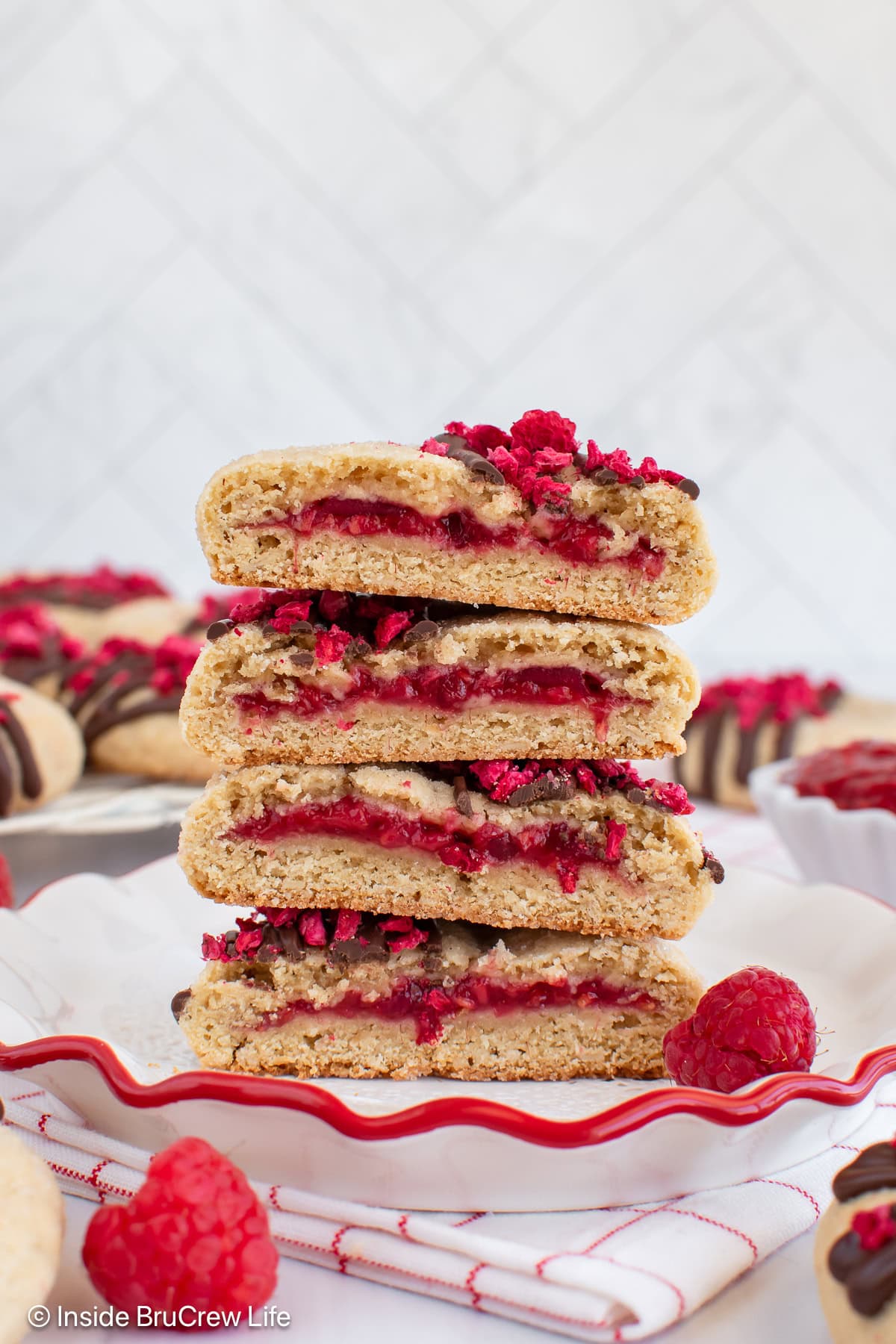 A stack of raspberry filled cookies cut in half so you can see the fruit filling.