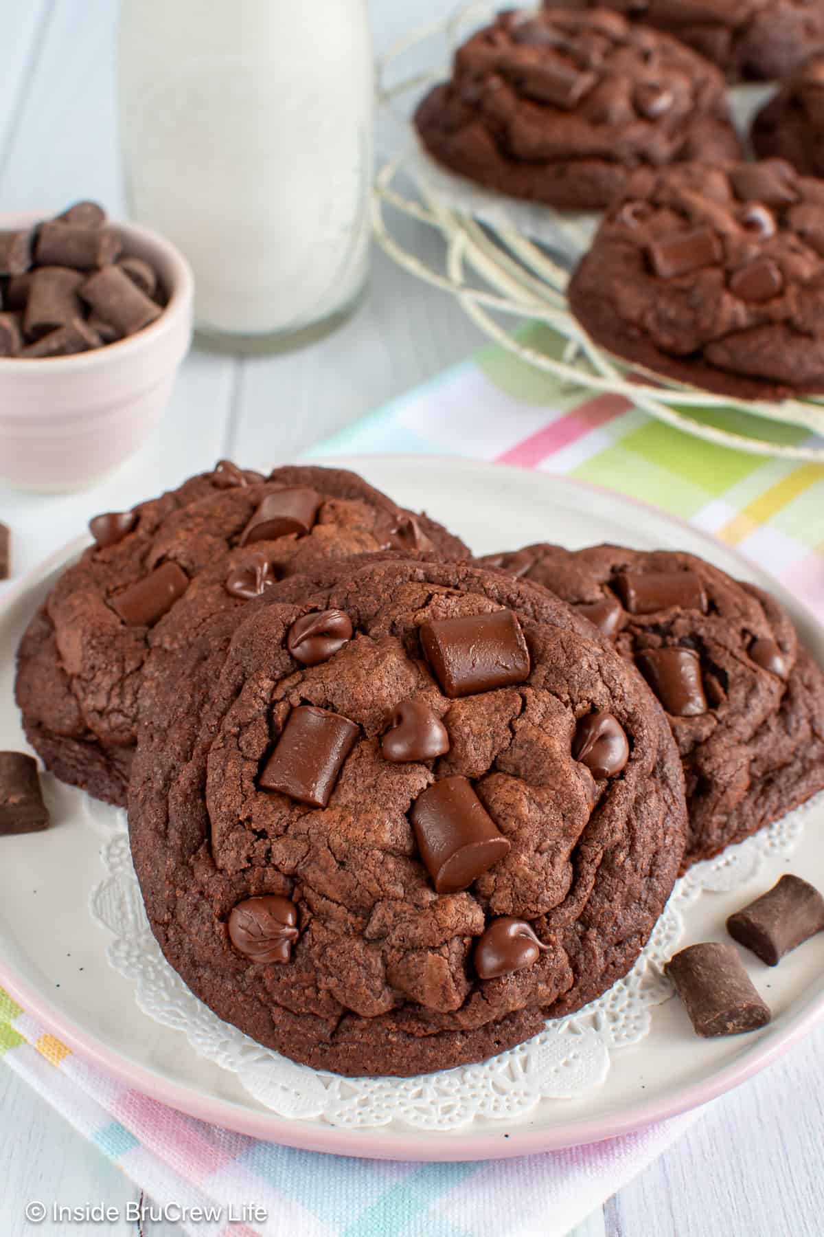 Three double chocolate chunk cookies stacked on a white plate.