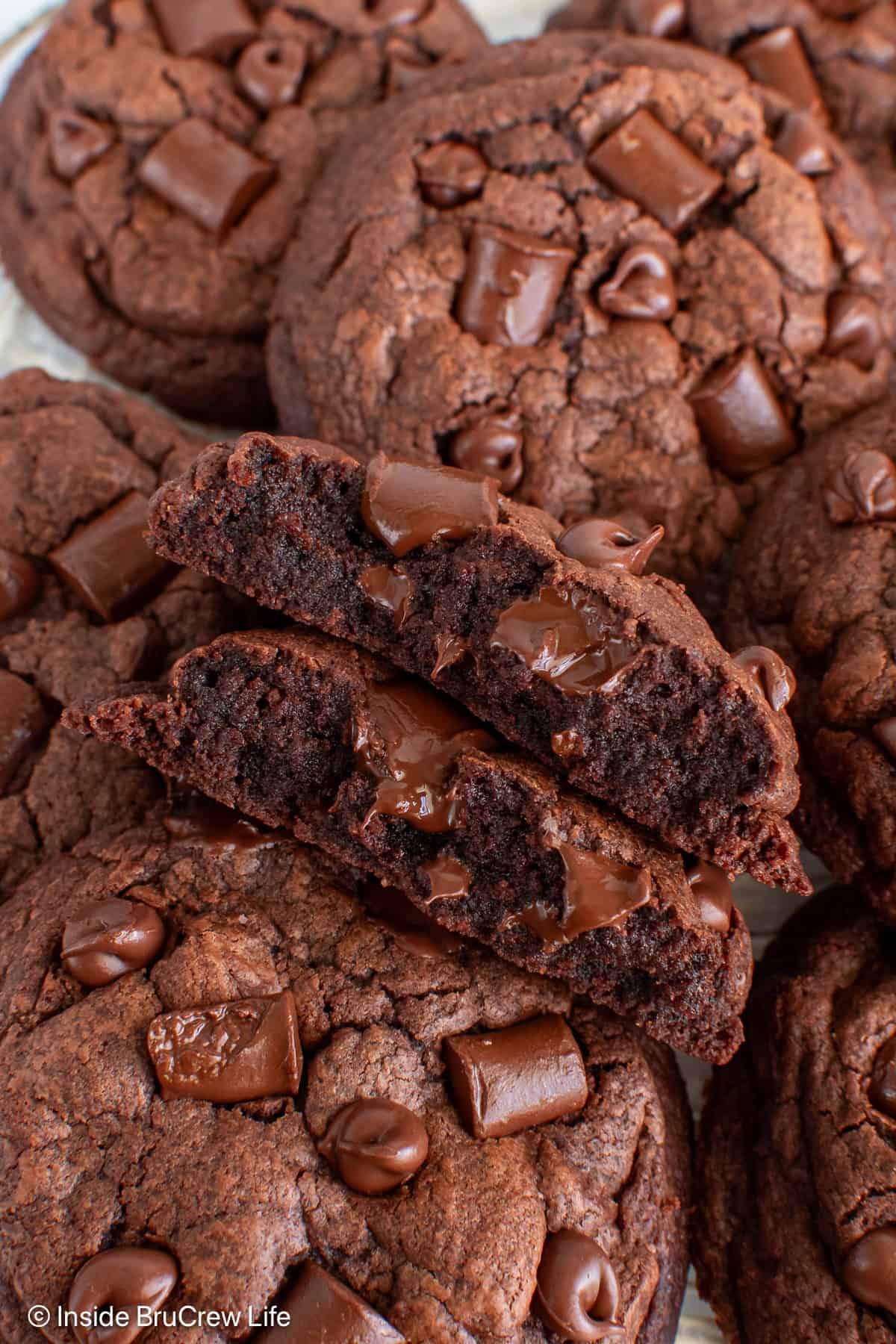 Overhead view of a plate of double chocolate chunk cookies with one broken in half.