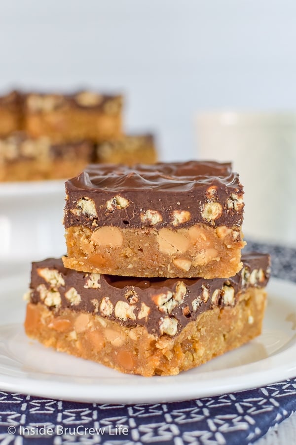 Two Take 5 cookie bars stacked together on a white plate with more bars behind it