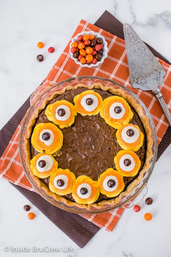 Overhead picture of a Candy Corn M&M Brownie Pie with swirls of orange, yellow, and white frosting around the edges