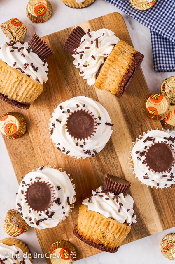 Overhead picture of a wooden cutting board with peanut butter cup cheesecakes sitting and lying down on it.