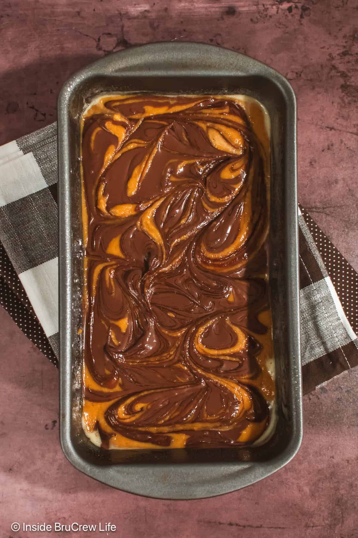 A pan with pumpkin bread batter swirled with Nutella.