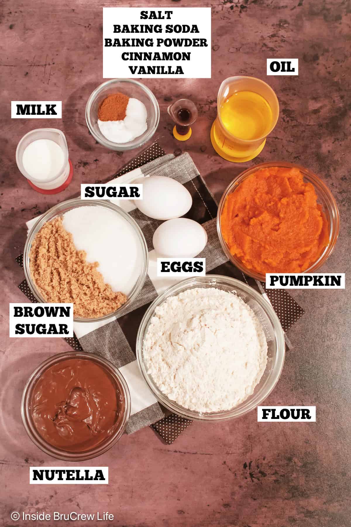 Ingredients for a pumpkin bread with a Nutella swirl on a brown background.